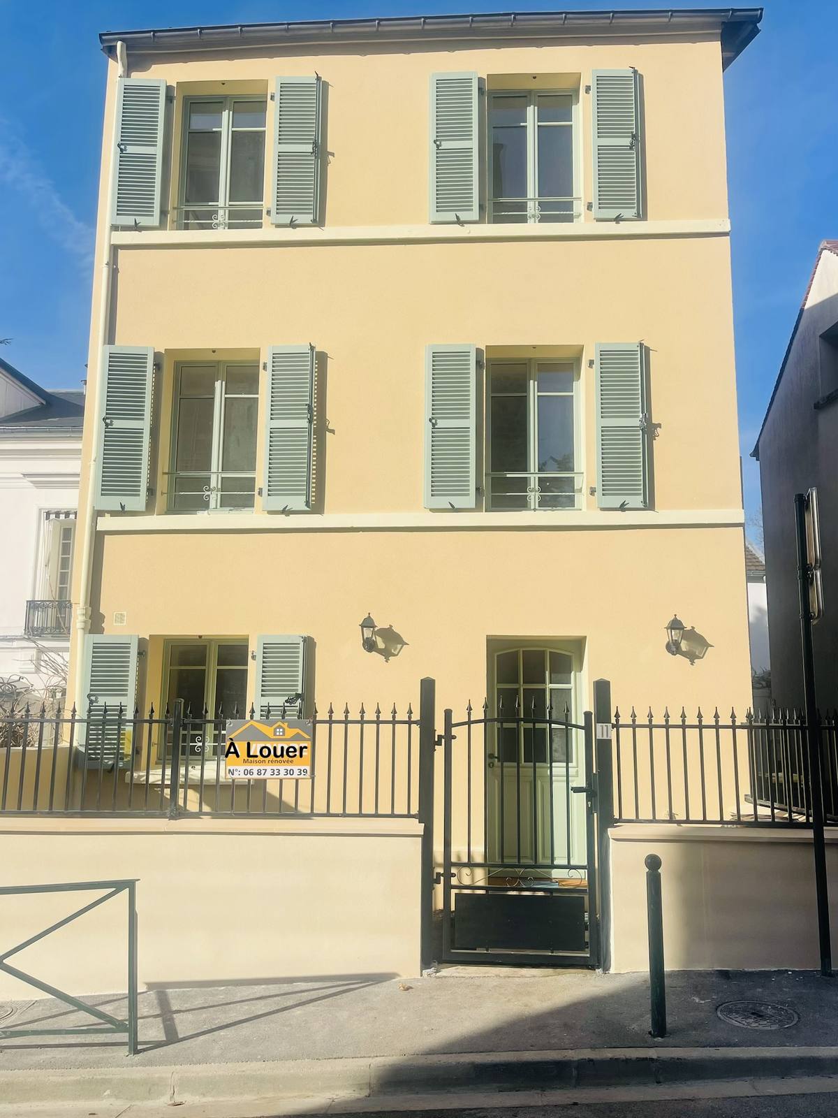 Façade rénovée, enduit jaune et volets vert d'eau